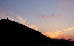Gellért-hegy a Szabadság-szoborral a Nap lenyugvása közben, szép fátyolfelhőkkel ékesítve.