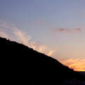 Gellért-hegy a Szabadság-szoborral a Nap lenyugvása közben, szép fátyolfelhőkkel ékesítve.